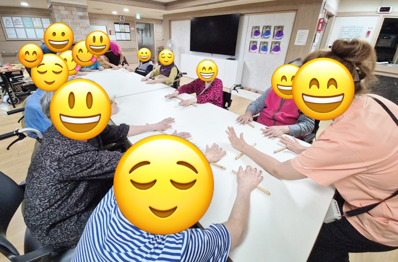 어르신들이 테이블 위에서 나무 막대를 손바닥으로 굴리며 손 운동을 하는 모습