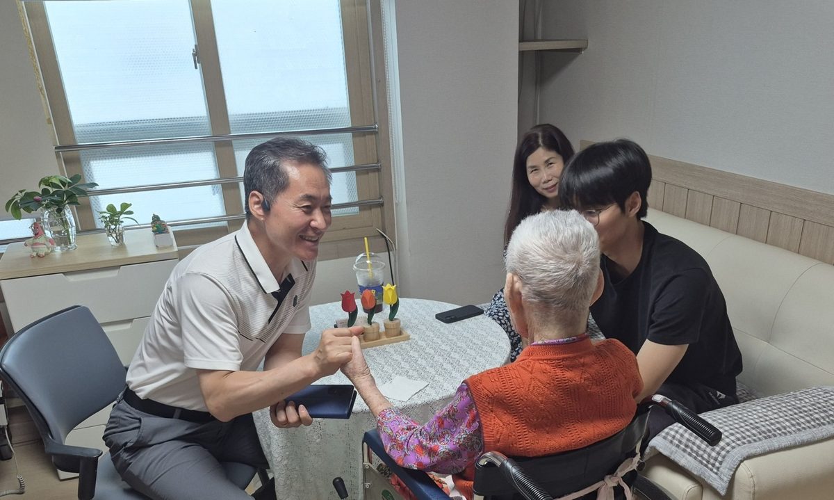 면회실에서 어르신, 가족과 함께 웃으며 이야기 나누는 원장